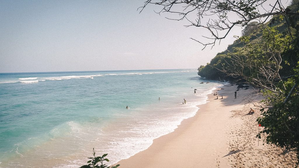 People swimming and surfing on Gunung Payung Beach in Bali