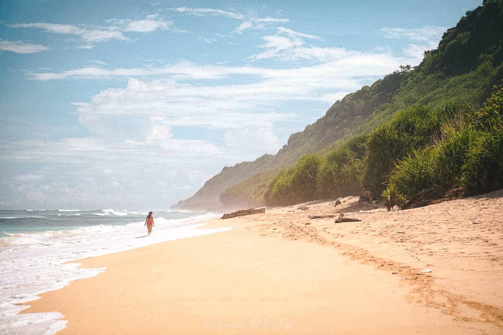 A beautiful scenic shoe with a woman walking on the shoreline on Nunggalan Beach in Uluwatu